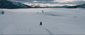 Movie still from “Wind River” (2017), directed by Taylor Sheridan – A person riding skis down a snow covered slope; Extreme Wide shot, High angle