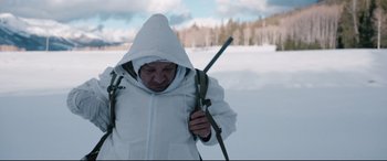 Movie still from “Wind River” (2017), directed by Taylor Sheridan – A man in a white jacket holding a stick in the snow; Medium shot, Low angle