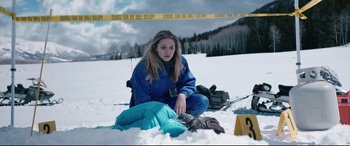 Movie still from “Wind River” (2017), directed by Taylor Sheridan – A woman sitting in the snow next to a sleeping bag; Medium shot, High angle