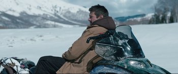 Movie still from “Wind River” (2017), directed by Taylor Sheridan – A man sitting on top of a motorcycle in the snow; Medium shot, High angle
