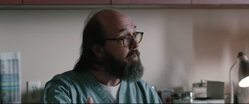 Movie still from “Wind River” (2017), directed by Taylor Sheridan – A man with a long beard and glasses is looking at the camera; Close Up shot, Over the shoulder angle