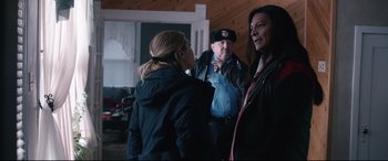 Movie still from “Wind River” (2017), directed by Taylor Sheridan – Two women and a police officer are standing in a room; Medium shot, Over the shoulder angle
