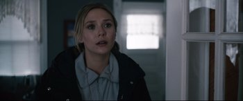 Movie still from “Wind River” (2017), directed by Taylor Sheridan – A woman in a black jacket is standing in a room; Close Up shot, Over the shoulder angle