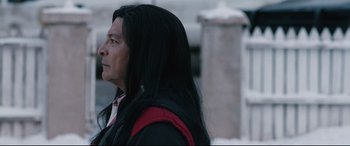 Movie still from “Wind River” (2017), directed by Taylor Sheridan – A man with long black hair is looking to his left; Close Up shot, Over the shoulder angle