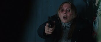 Movie still from “Wind River” (2017), directed by Taylor Sheridan – A woman holding a gun in a dark room; Close Up shot, Low angle