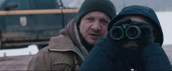 Movie still from “Wind River” (2017), directed by Taylor Sheridan – A man in a winter coat and a hat is holding a camera; Close Up shot, Over the shoulder angle