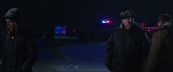 Movie still from “Wind River” (2017), directed by Taylor Sheridan – A man standing next to a police car in the dark; Medium shot, Low angle