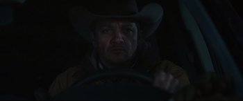 Movie still from “Wind River” (2017), directed by Taylor Sheridan – A man wearing a cowboy hat driving a car at night; Close Up shot, Low angle