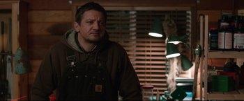 Movie still from “Wind River” (2017), directed by Taylor Sheridan – A man standing in front of a wooden wall; Medium shot, Over the shoulder angle