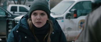Movie still from “Wind River” (2017), directed by Taylor Sheridan – A young woman wearing a hat and a jacket; Close Up shot, Over the shoulder angle