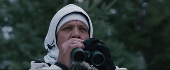 Movie still from “Wind River” (2017), directed by Taylor Sheridan – A man in a white jacket and a white hat looking through binoculars; Close Up shot, Low angle