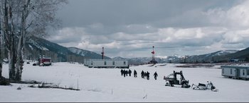 Movie still from “Wind River” (2017), directed by Taylor Sheridan – A group of people walking across a snow covered field; Extreme Wide shot, High angle
