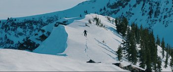 Movie still from “Wind River” (2017), directed by Taylor Sheridan – A person is skiing down a mountain slope; Extreme Wide shot, High angle