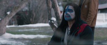 Movie still from “Wind River” (2017), directed by Taylor Sheridan – A man with blue face paint sitting in the snow; Medium shot, Over the shoulder angle