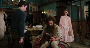 Movie still from “Dolittle” (2020), directed by Stephen Gaghan – A man sitting on the floor of a living room while a woman stands next to him; Medium shot, Over the shoulder angle