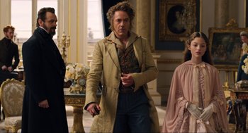 Movie still from “Dolittle” (2020), directed by Stephen Gaghan – A man in a trench coat holding a cigarette in his mouth; Medium shot, Over the shoulder angle