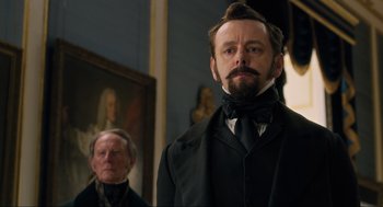 Movie still from “Dolittle” (2020), directed by Stephen Gaghan – A man in a suit and a man in a black tie; Close Up shot, Low angle