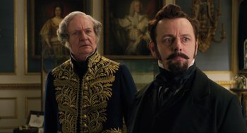 Movie still from “Dolittle” (2020), directed by Stephen Gaghan – Two men standing next to each other in front of a painting; Medium shot, Over the shoulder angle