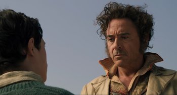 Movie still from “Dolittle” (2020), directed by Stephen Gaghan – A man with curly brown hair and a green shirt is talking to another man; Close Up shot, Over the shoulder angle