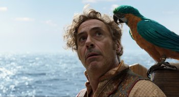 Movie still from “Dolittle” (2020), directed by Stephen Gaghan – A parrot sitting on the shoulder of a man; Close Up shot, Over the shoulder angle