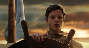 Movie still from “Dolittle” (2020), directed by Stephen Gaghan – A young man holding on to a steering wheel of a boat; Close Up shot, Low angle