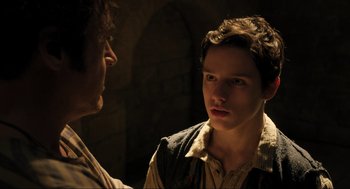 Movie still from “Dolittle” (2020), directed by Stephen Gaghan – A young man talking to another young man in a dark room; Close Up shot, Over the shoulder angle