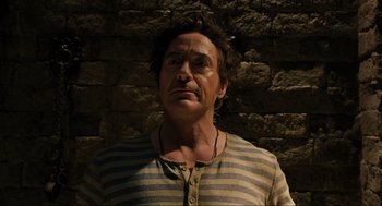 Movie still from “Dolittle” (2020), directed by Stephen Gaghan – A person wearing a striped shirt near a brick wall; Close Up shot, Low angle