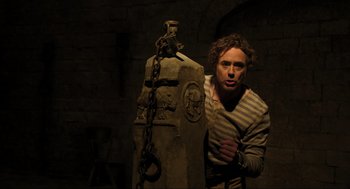 Movie still from “Dolittle” (2020), directed by Stephen Gaghan – A man standing next to a fire hydrant chained to a pole; Medium shot, Low angle