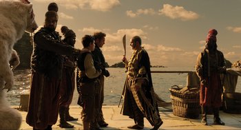 Movie still from “Dolittle” (2020), directed by Stephen Gaghan – A group of people standing on a dock next to the ocean; Wide shot, Over the shoulder angle