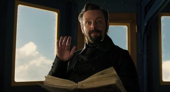 Movie still from “Dolittle” (2020), directed by Stephen Gaghan – A man in a black jacket is holding a book; Medium shot, Low angle