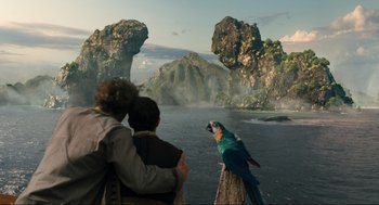 Movie still from “Dolittle” (2020), directed by Stephen Gaghan – Two people looking at a bird on a tree stump; Wide shot, Over the shoulder angle