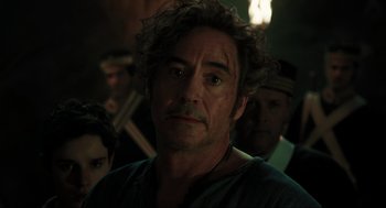 Movie still from “Dolittle” (2020), directed by Stephen Gaghan – A person with a group of people in the background; Close Up shot, Over the shoulder angle