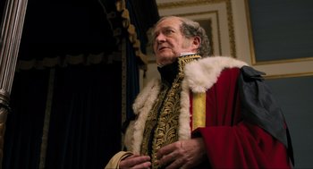 Movie still from “Dolittle” (2020), directed by Stephen Gaghan – An older man in a red and gold outfit; Medium shot, Low angle