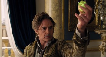 Movie still from “Dolittle” (2020), directed by Stephen Gaghan – A man holding a piece of food in his hand; Close Up shot, Over the shoulder angle