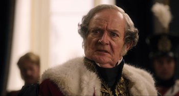 Movie still from “Dolittle” (2020), directed by Stephen Gaghan – An old man in a fur coat and a black and gold jacket; Close Up shot, Over the shoulder angle