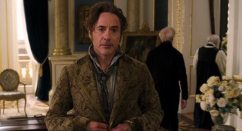 Movie still from “Dolittle” (2020), directed by Stephen Gaghan – A man in a brown jacket standing next to a painting; Close Up shot, Over the shoulder angle