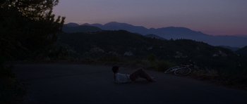 Movie still from “Donnie Darko” (2001), directed by Richard Kelly – A person laying on the ground in the dark; Extreme Wide shot, High angle
