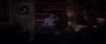 Movie still from “Donnie Darko” (2001), directed by Richard Kelly – A man reading a book in a dark room; Wide shot, High angle