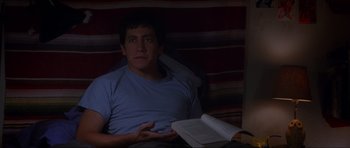 Movie still from “Donnie Darko” (2001), directed by Richard Kelly – A man sitting in a chair with a book in his lap; Medium shot, High angle