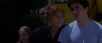 Movie still from “Donnie Darko” (2001), directed by Richard Kelly – A person smiling with a person standing next to them; Close Up shot, Over the shoulder angle