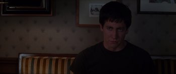 Movie still from “Donnie Darko” (2001), directed by Richard Kelly – A man sitting in front of a picture on the wall; Close Up shot, Over the shoulder angle