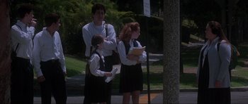 Movie still from “Donnie Darko” (2001), directed by Richard Kelly – A man and two young girls standing next to each other on the sidewalk; Medium shot, Low angle