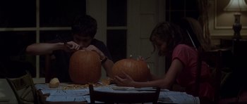Movie still from “Donnie Darko” (2001), directed by Richard Kelly – Two people sitting at a table with pumpkins; Medium shot, Low angle