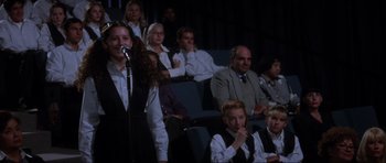 Movie still from “Donnie Darko” (2001), directed by Richard Kelly – A group of people sitting in a room with a microphone; Medium shot, High angle