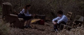 Movie still from “Donnie Darko” (2001), directed by Richard Kelly – Two people sitting in the woods near a radio; Wide shot, Low angle