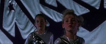 Movie still from “Donnie Darko” (2001), directed by Richard Kelly – Two young girls are standing in front of a projection screen; Close Up shot, Low angle