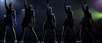 Movie still from “Donnie Darko” (2001), directed by Richard Kelly – A group of people in a dark room performing a dance move; Wide shot, Low angle