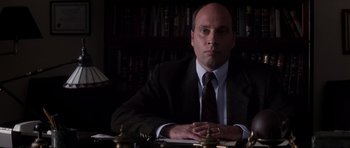 Movie still from “Donnie Darko” (2001), directed by Richard Kelly – A man sitting at a desk in a suit and tie; Close Up shot, Low angle