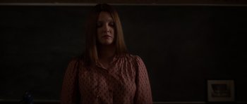 Movie still from “Donnie Darko” (2001), directed by Richard Kelly – A woman in a pink shirt is standing in a dark room; Medium shot, Over the shoulder angle