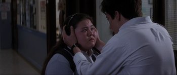 Movie still from “Donnie Darko” (2001), directed by Richard Kelly – A man is helping a woman put on a headband; Close Up shot, Over the shoulder angle